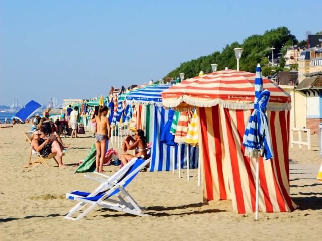 Deauville Beach, Normandy, France-First made famous in 1913 when Coco Chanel opened her first boutique in town, Deauville Beach is unmistakable with its brightly-colored, striped umbrellas and its picturesque boardwalk.