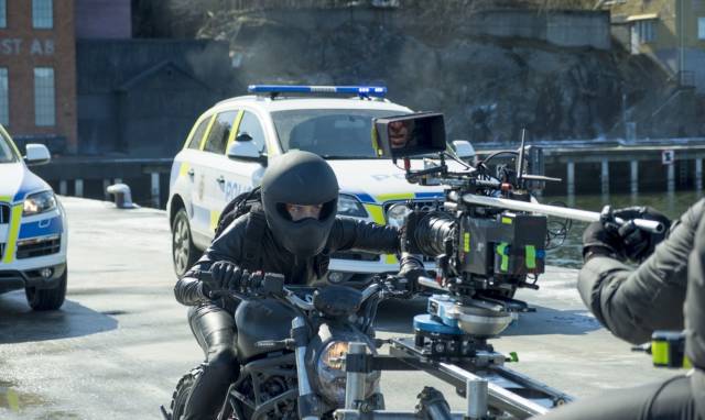 movie set photo of many cameras on a motorcycle rider and police cars in the background