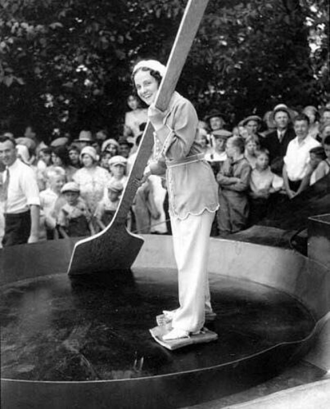 A woman in a giant frying pan with bacon tied to her feet before 7,200 eggs are added to a record-breaking omelet, USA, 1931