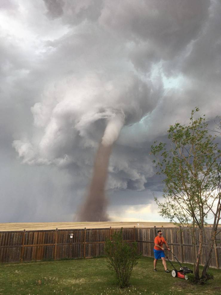 man mows lawn with tornado behind him
