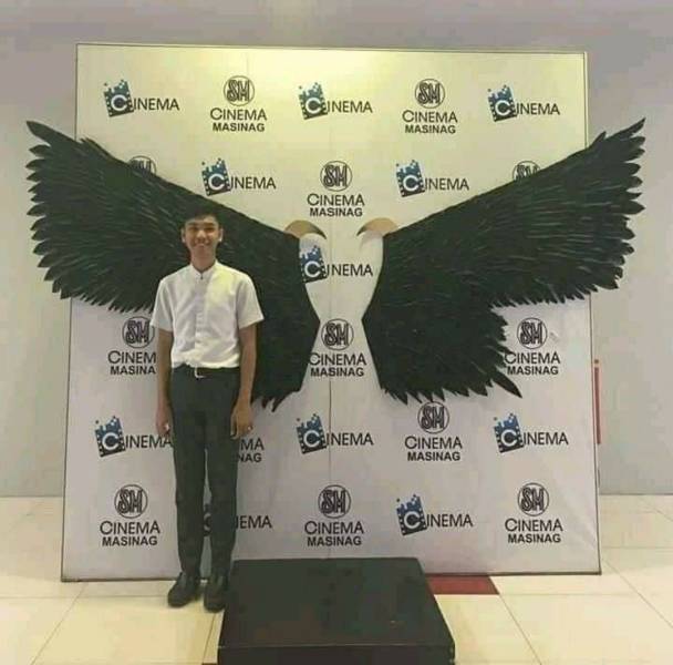 kid standing next to a giant pair of wings