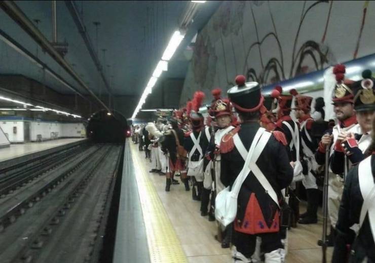 guys dressed in old colonial outfits waiting inside a subway station