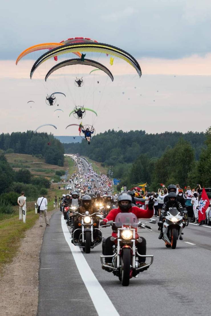 parachuters flying over motorcycle parade