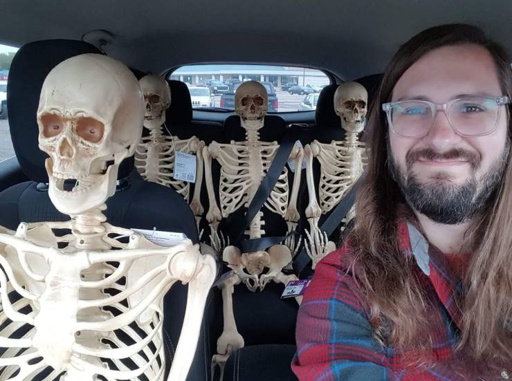 funny pics - guy hanging out in his car with a bunch of skeletons