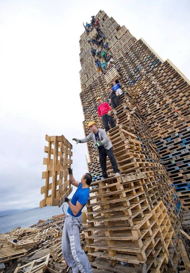funny random photos - people stacking wooden palettes to make worlds biggest bonfire