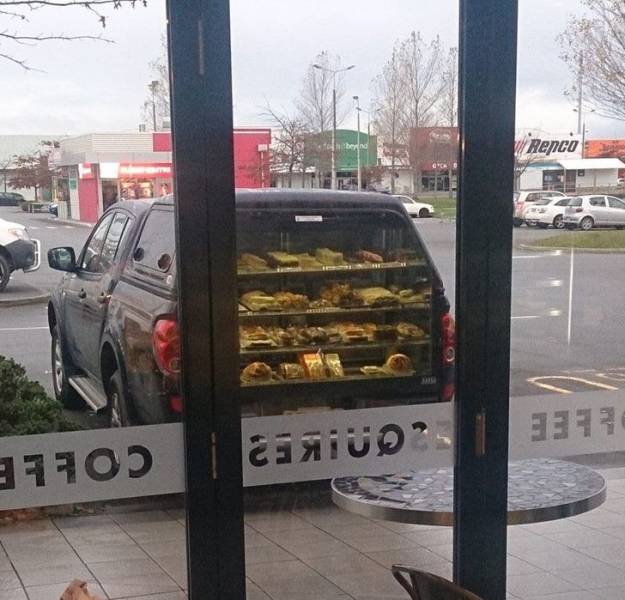 The reflection of this coffee shop window makes it look like this car sells pies out of its trunk