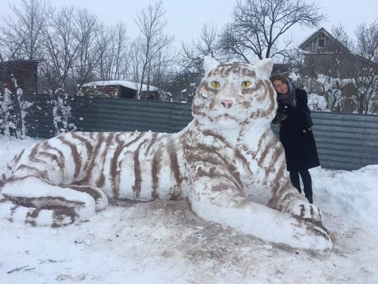cool pics - woman standing next to snow leopard sculpture made from snow