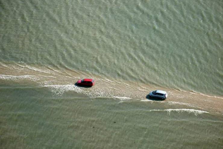 cool funny pics - cars driving on narrow strip of sand near water