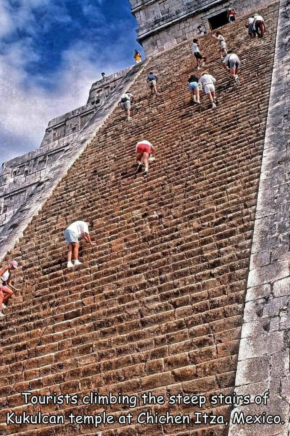 tourism - Tourists climbing the steep stairs of Kukulcan temple at Chichen Itza, Mexico.