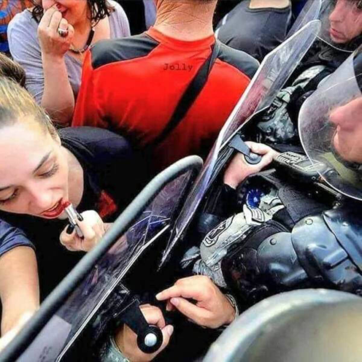 woman fixing lipstick in riot shield - Jolly