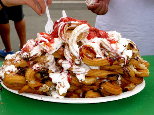 Mexican funnel cake churros, whipped cream, chocolate sauce, and strawberries