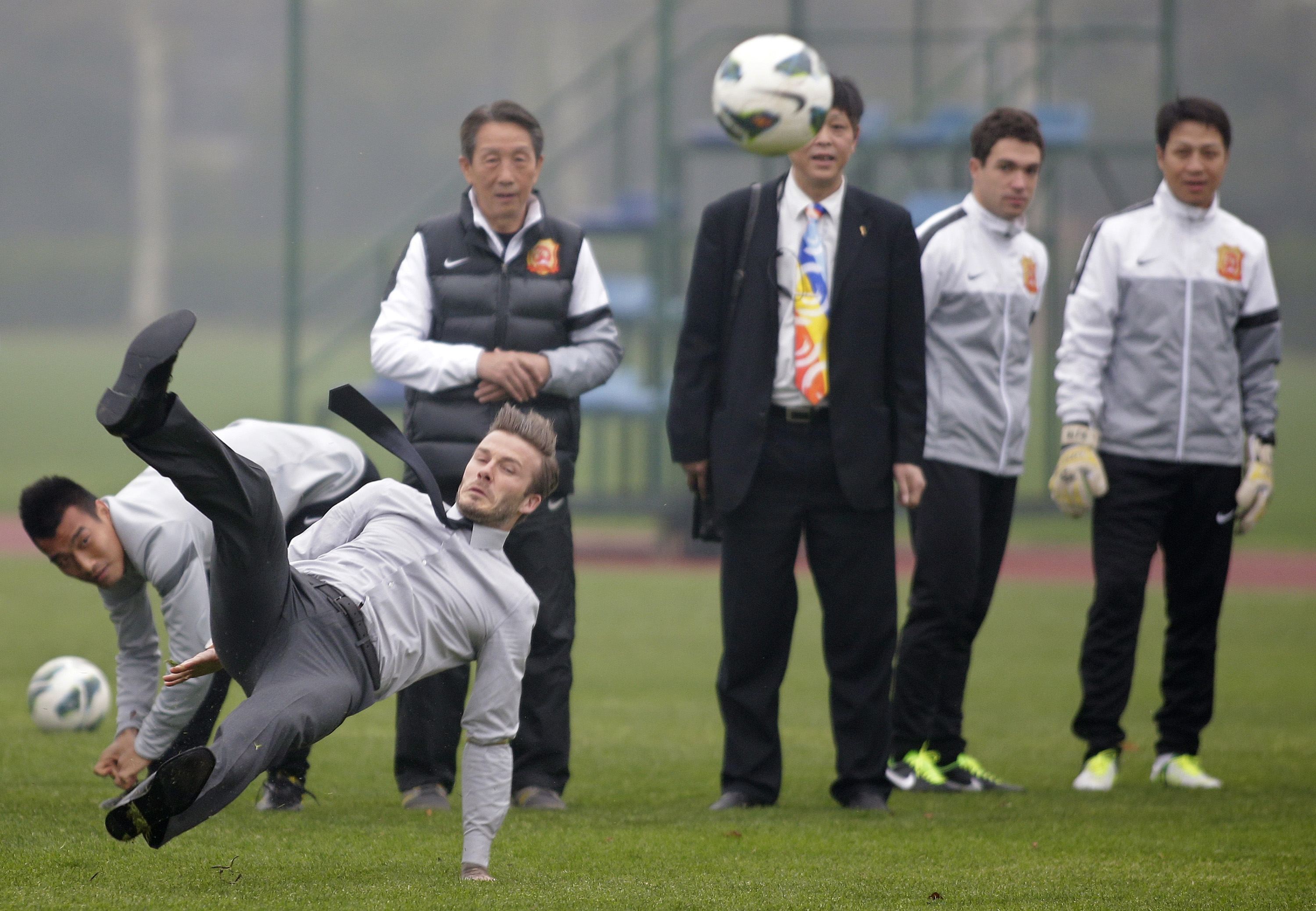 David Beckham slips as he free kicks at a sports field during his visit in Wuhan, Hubei province