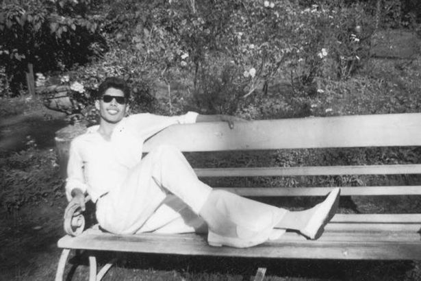 Freddie Mercury poses on a park bench