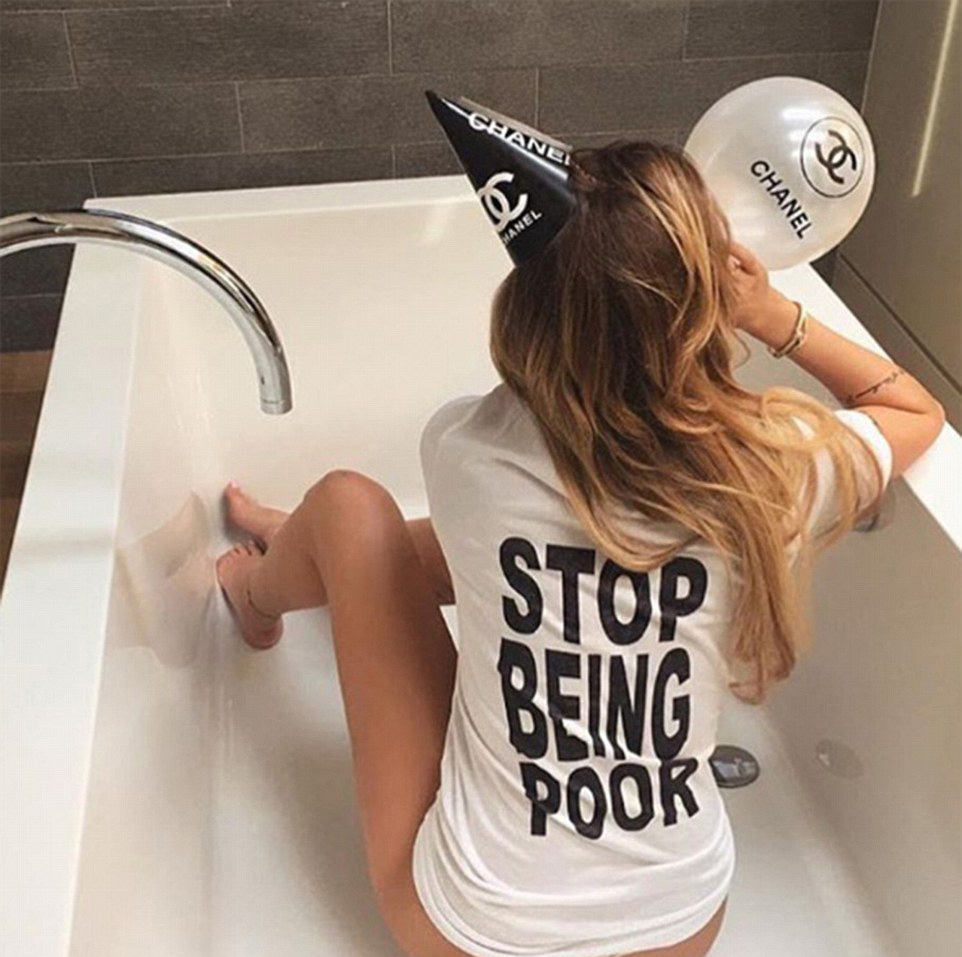 One woman brazenly sits in an empty bath tub while dressed in a Chanel paper hat and a T-shirt emblazoned with the slogan, 'stop being poor'