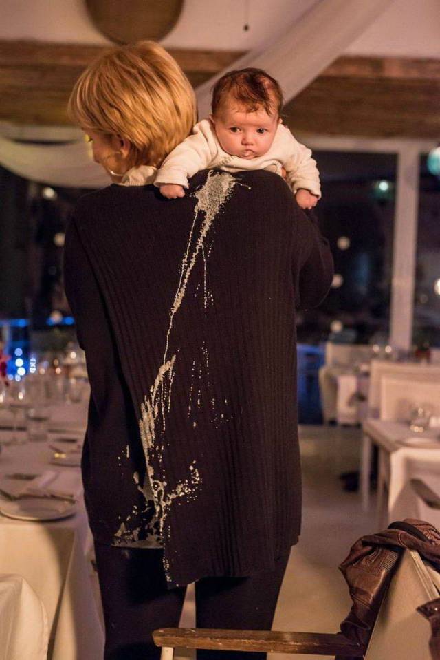 random baby picture of throwing up all over mom's back at an event