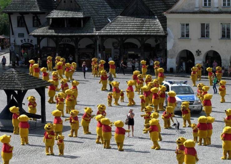 Cursed image of 30 people in Winnie the Pooh costumes in a town square
