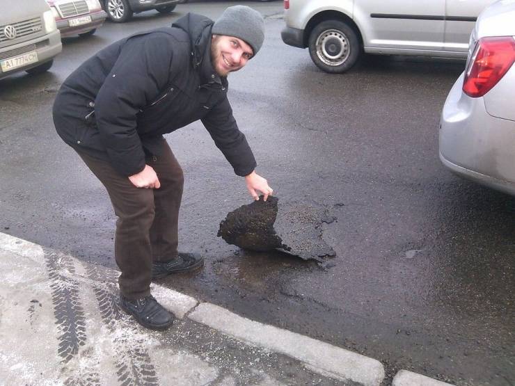 Cursed image of Guy picking up a piece of tar off the street that's covering a pot hole