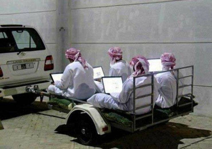 Cursed image of four arabic men on laptops being towed behind an SUV