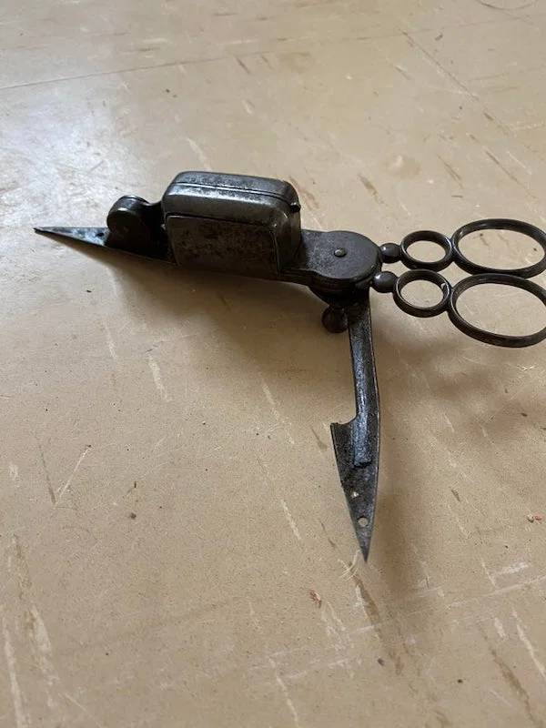 "Found clearing a house, works like a pair of scissors except for the pointy thing at the bottom which just swivels"A: "It’s a candle snuffer. Candle snuffer scissors."