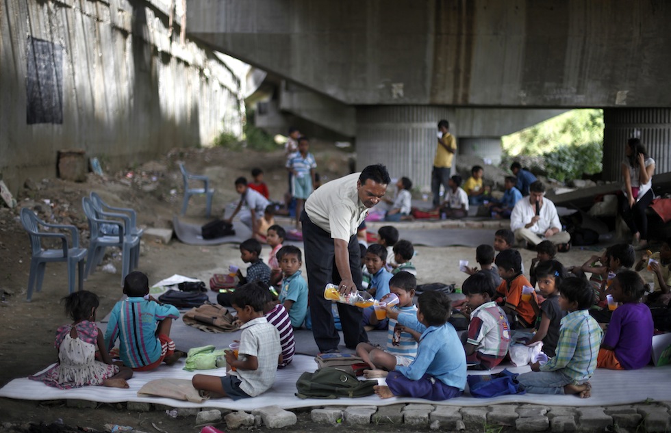 For two hours every weekday, Rajesh Kumar Sharma leaves his day job at a local general store and walks to a spot under a bridge where a crowd of children gathers.