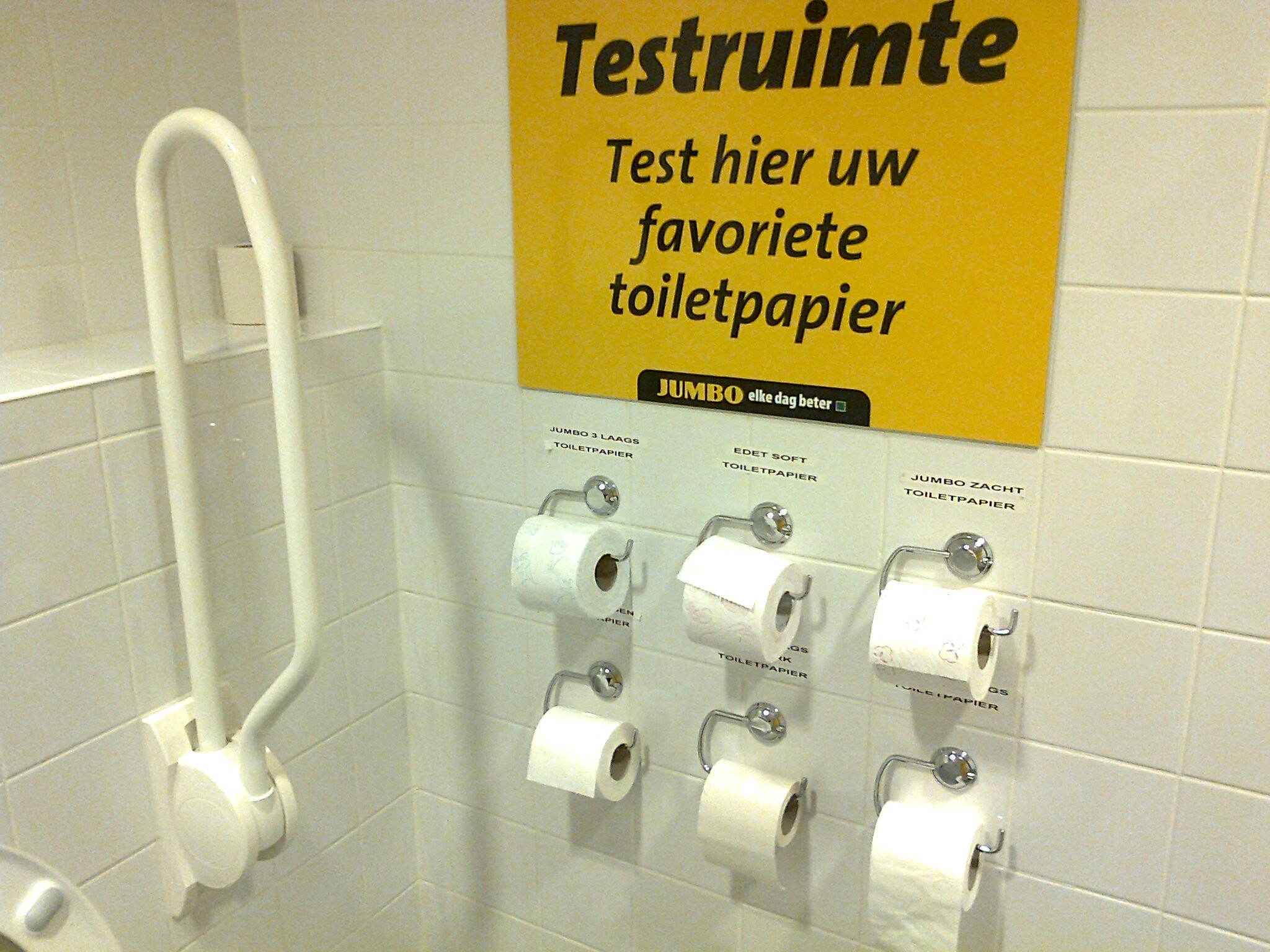 There is a bathroom in a Dutch grocery store with various brands of toilet paper so customers can test them out before they purchase.