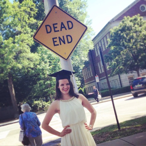 Girl about to graduate standing in front of Dead End sign
