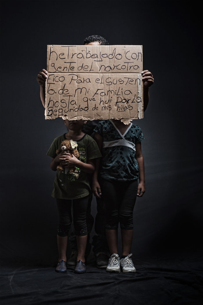 Anonymous person with daughters hidden behind cardboard to protect their identity. The message says, “I have worked with drug traffickers (in Honduras) to support my family, until I fled only to find safety for my children”.