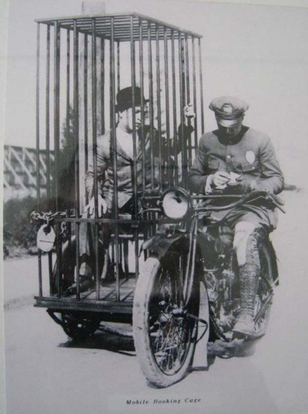 A police officer on a Harley-Davidson transports a prisoner in a holding cell - 1921.