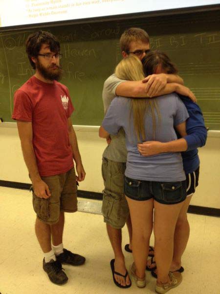 group of people hugging near a guy that's alone