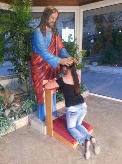 Funny dirty picture of a girl kneeling infront of a Jesus statue as if to perform a BJ.