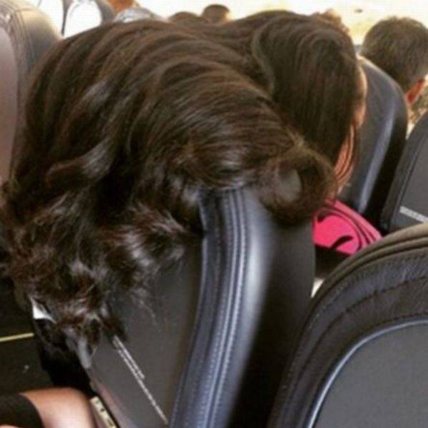 mildly infuriating picture of woman with her hair on an airplane clearing violating the personal space of the seat behind her