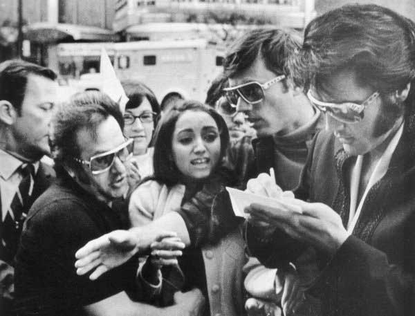 A young Elvis Presley signs an autograph for Madonna.