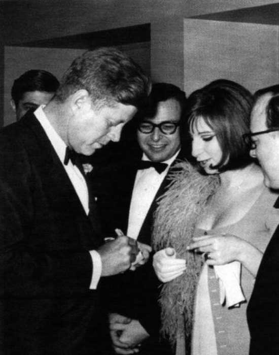 John F. Kennedy signs an autograph for Barbra Streisand. 