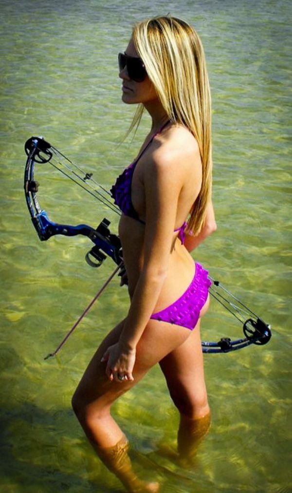 Cute girl holding an archery bow while standing in shallow water