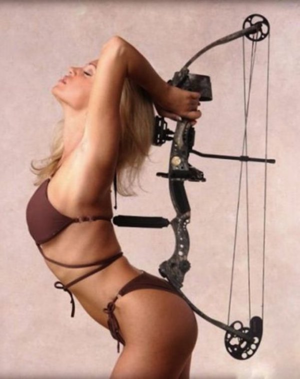 Girl in maroon bikini posing erotically with a bow and arrow.