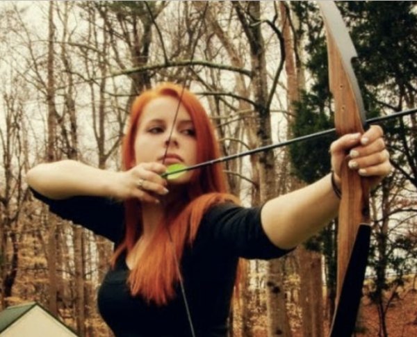 Red haired woman firing a classical bow and arrow