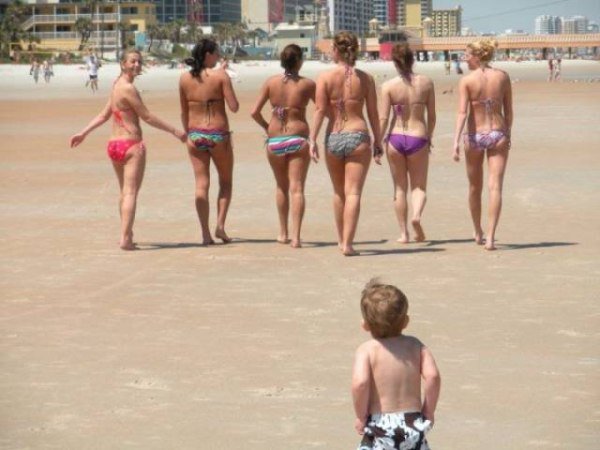 Funny pic of kid on the beach staring at women in bikini's walking away.