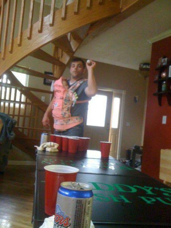 Beer pong while holding and wearing an infant.