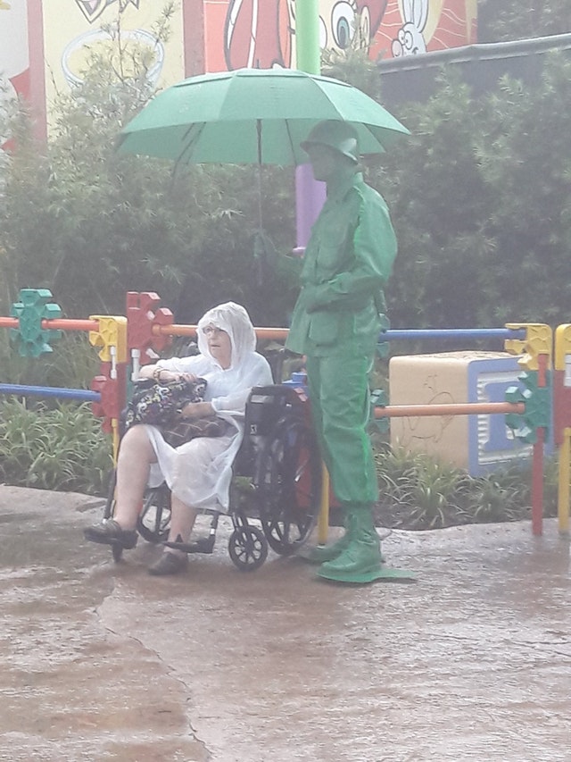 guy holding an umbrella for an old lady