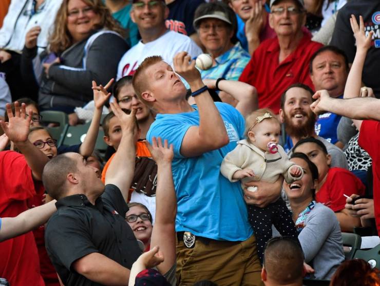 funny pics and memes - Guy holding a baby at a baseball game about to be hit in the face with the ball