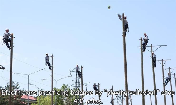 Volleyball - Electricians practicing balance by playing volleyball" atop 40' poles.