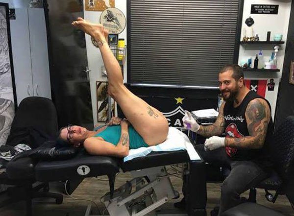 Picture of woman on the tattoo artist's table with her legs in the air.