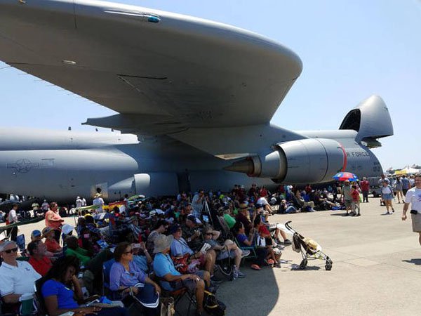 People sitting under the shade of an airplane wing.
