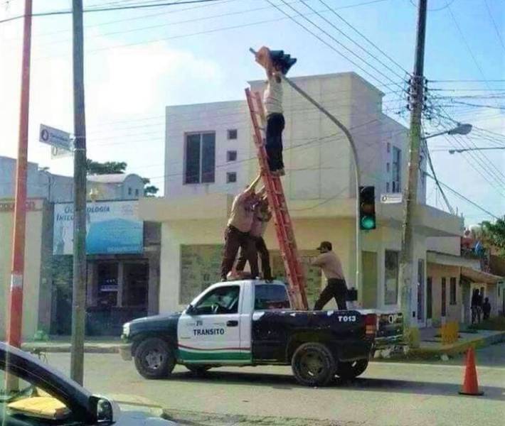 people holding a ladder up in the back of a pick-up truck