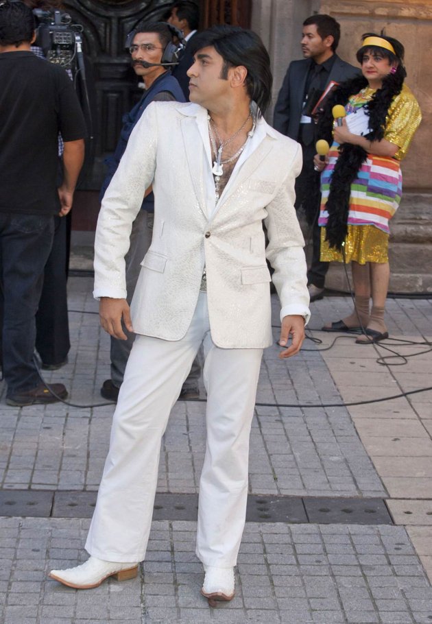 A Mexican celebrity attending a celebrities wedding in Mexico. I don't know whats more disturbing: his outfit or the guy on the back right corner dressed as i don't know WTF!