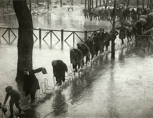 Hundreds of people walk across a walkway of chairs, during floods in Paris.