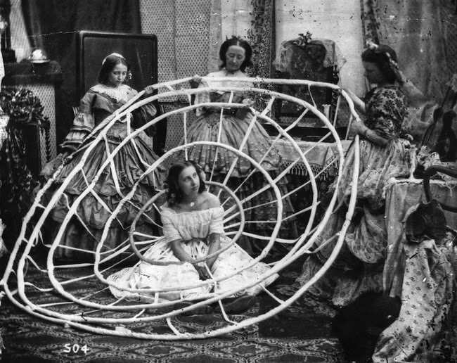 A woman waits for her massive hoops to be completed, in a London dress shop, 1860.