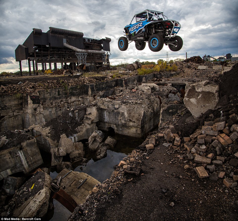 A turbocharged off-road vehicle performs a spectacular jump through the second storey of a derelict building: