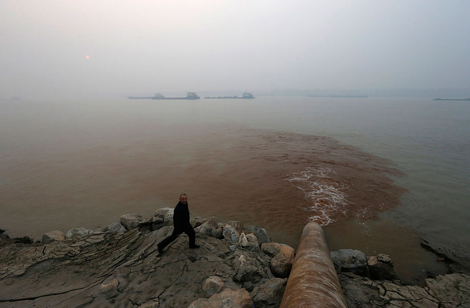 Man Walks By A Pipe Discharging Waste Water Into The Yangtze River