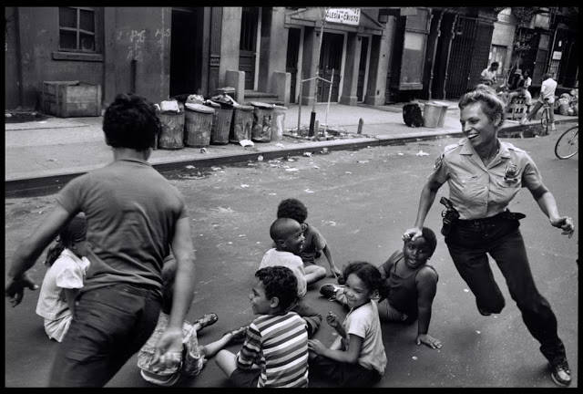 A police officer playing with children on the streets of Harlem in 1978.